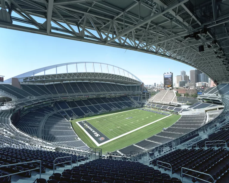 Daylight view of the seating bowl at Lumen Field, looking down on the Seattle Seahawks football field and the city's skyline beyond