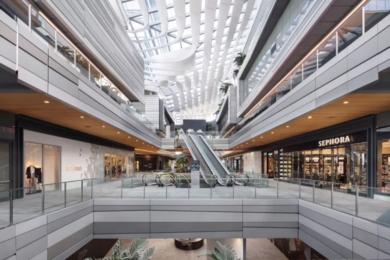 Interior daylight view of retail shops on three levels of Brickell City Centre with a skylight ceiling and central escalators