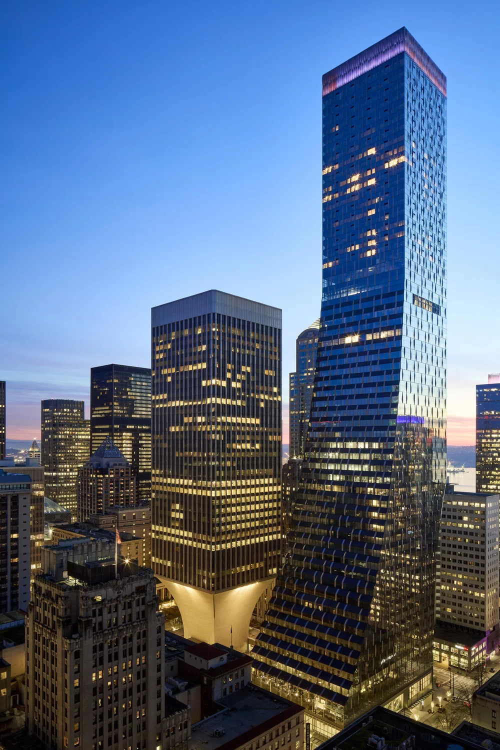Exterior twilight view of Rainier Square's 58-story glass facade with surrounding downtown Seattle high-rise buildings