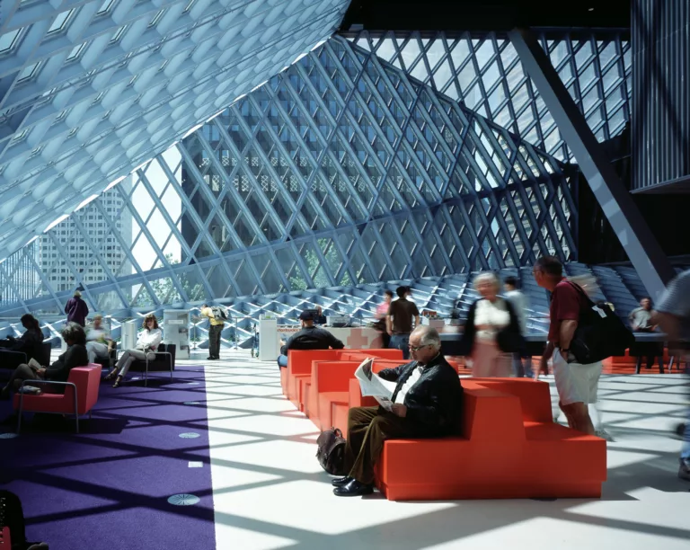 Interior daylight view of a populated reading room surrounded by Seattle Central Library’s angular, steel-and-glass walls