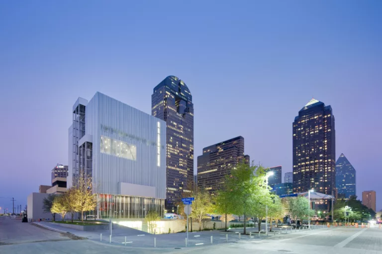 A twilight view of the Dee and Charles Wyly Theatre amidst the city's skyline