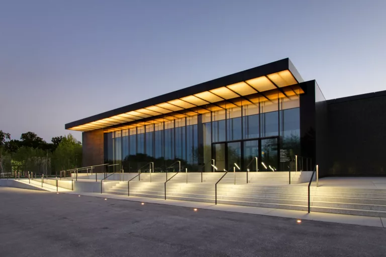 Exterior twilight view of the illuminated steps leading toward the glass-enclosed addition to the St. Louis Art Museum Renovation and Expansion