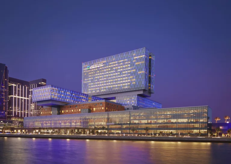 Exterior twilight view of the 24-story Cleveland Clinic Abu Dhabi waterfront medical center and its iconic "floating" patient tower