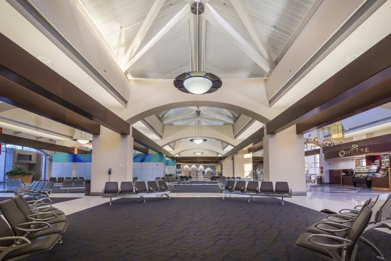 Interior image of gate seating, coffee shop, and dome-shaped, ceiling-mounted light fixtures at the expanded McAllen-Miller International Airport