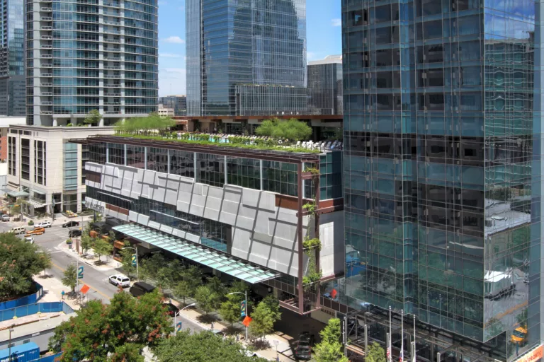 Aerial daylight view of the 35-story JW Marriott Austin rising from a six-story podium surrounded by roadway traffic and nearby high-rise buildings