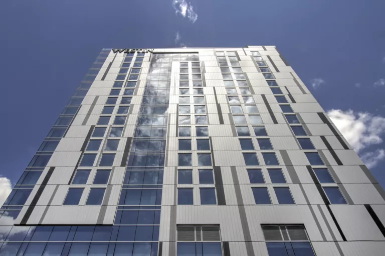 Exterior daylight view looking up at the 17-story Westin Austin Downtown with clouds reflected in the structure's steel-and-glass facade