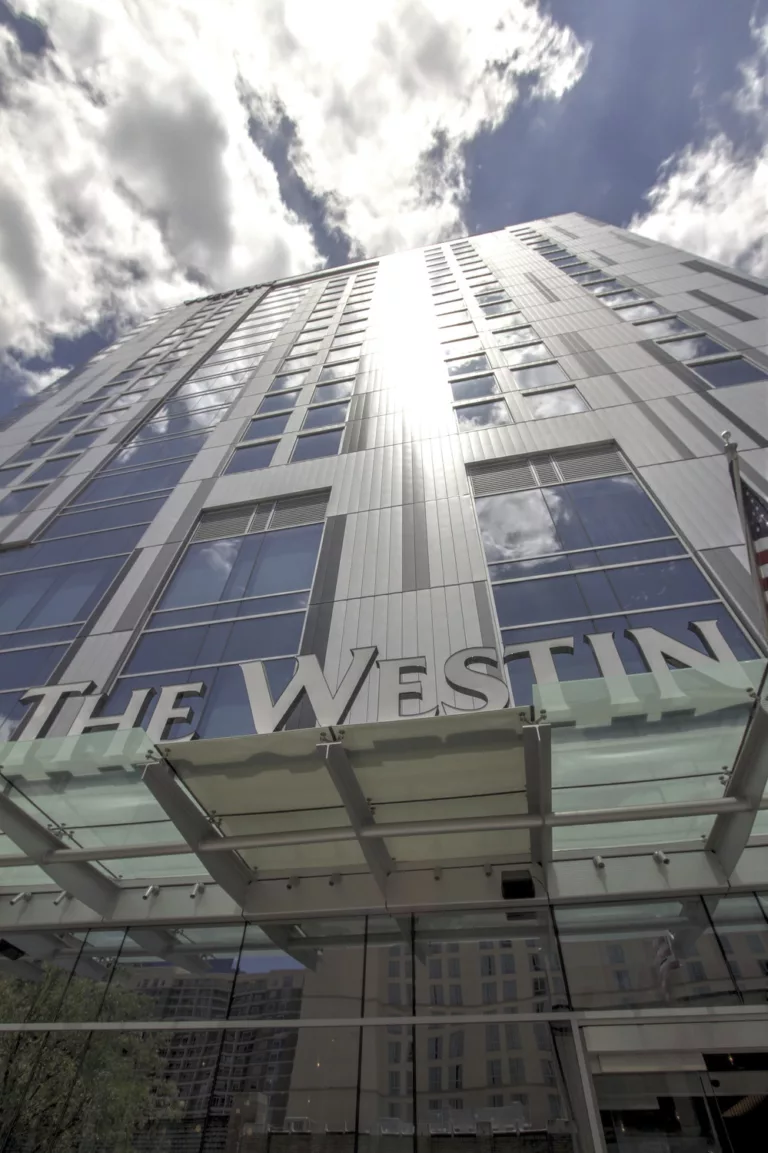 Exterior daylight view looking up at Westin Austin Downtown's 17-story, steel-and-glass facade with signage