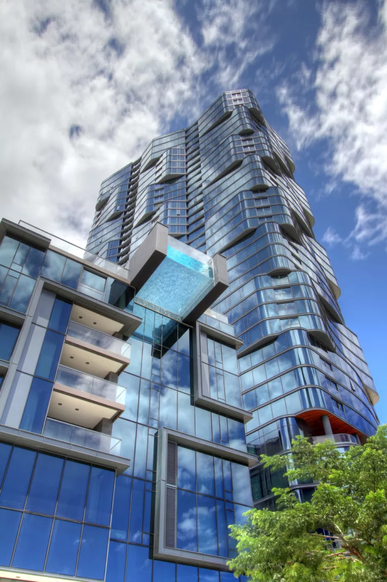 Exterior daylight view looking up at Anaha's 37-story, rolling-glass façade and glass-bottom infinity pool cantilevered 15 feet off the building's edge and 75 feet above the street