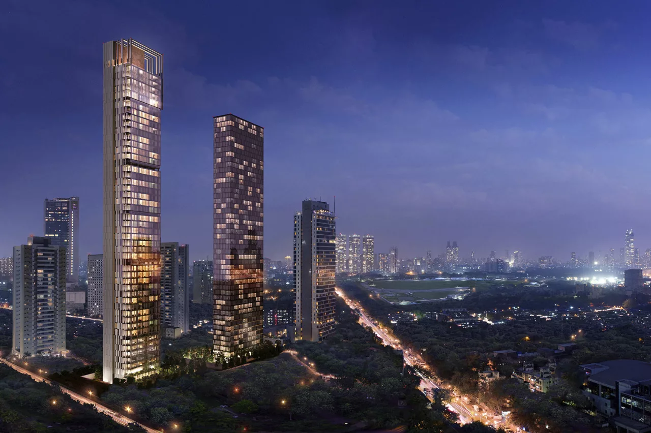 Exterior twilight view of the slender, 56-story Mumbai Four Seasons Residential Tower surrounded by six other high-rise buildings, street lights and vehicle traffic below, and the distant skyline