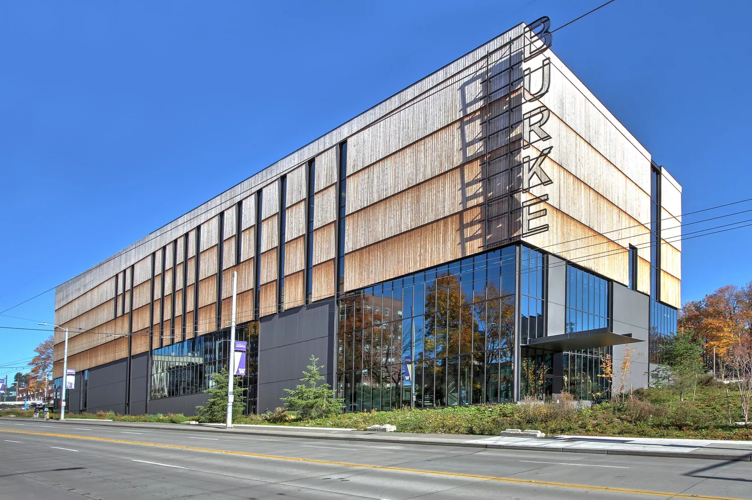 A daylight view of the southwest corner of the New Burke Museum's glass and wood exterior with vertical signage