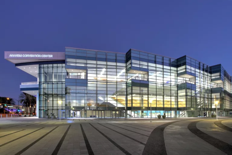 Exterior twilight view of the Anaheim Convention Center Expansion illuminated from within and featuring a large outdoor plaza