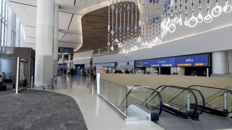 Interior of San Francisco International Airport's Harvey Milk Terminal 1 with views of check-in gates, escalators, and decorative overhead lighting