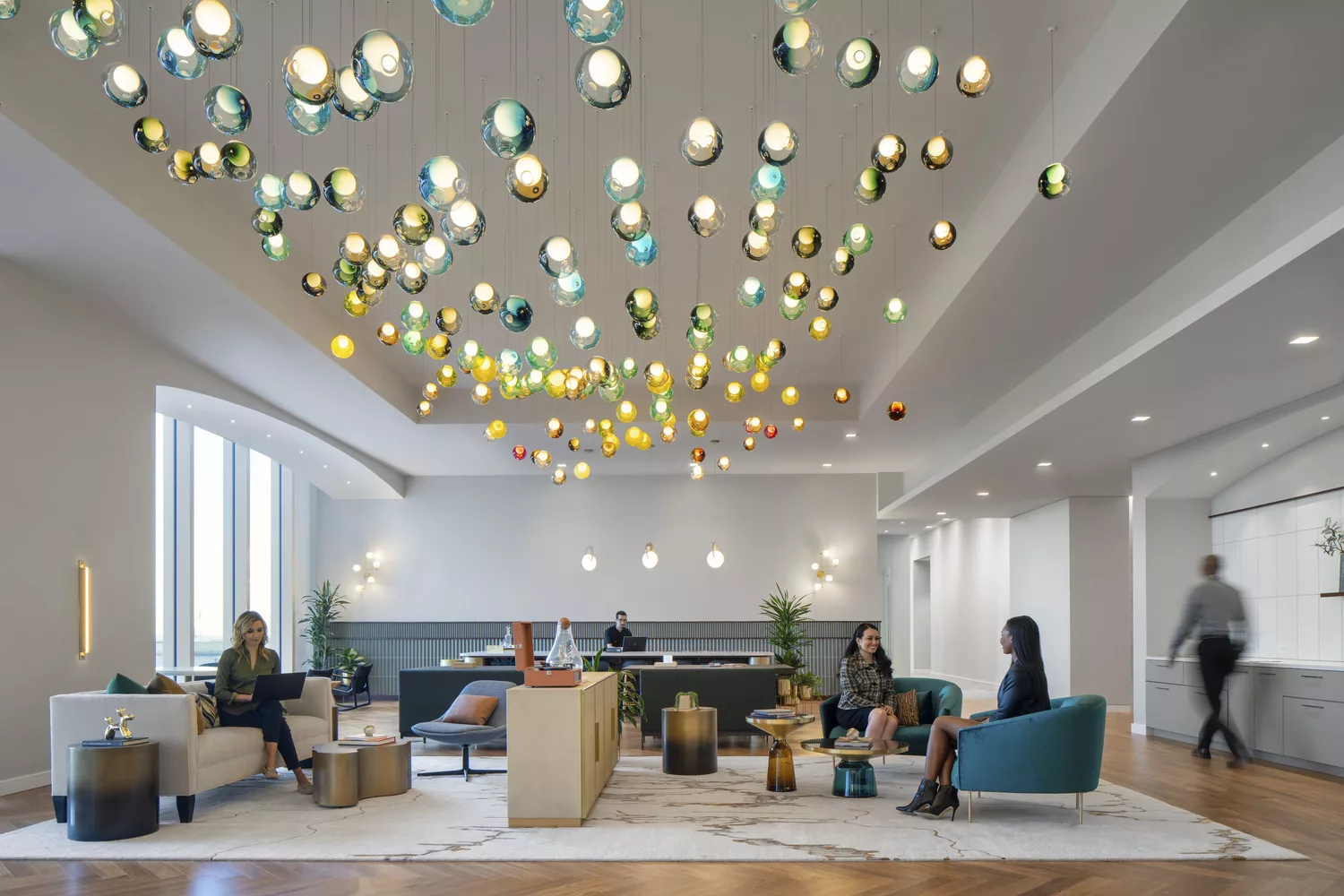 Interior daylight view of flexible workspace inside Texas Tower with work tables, sofa seating, and decorative overhead lights