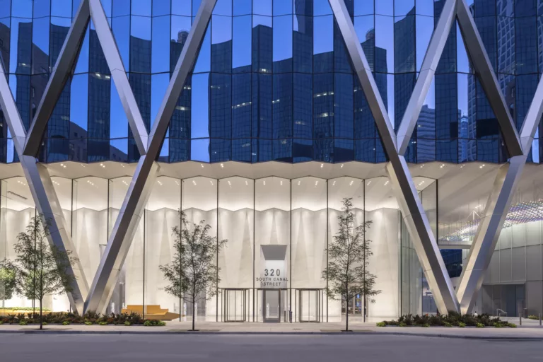 Exterior twilight view of the 50-story BMO Tower's grand lobby entrance framed by V-shaped structural facade columns