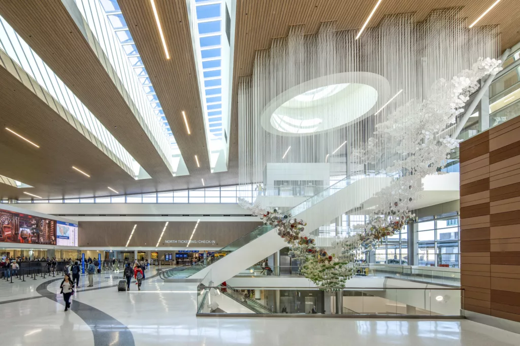 Interior daylight image of Nashville International Airport's Terminal Lobby with skylights, escalators, ticketing terminals, and passenger security lines