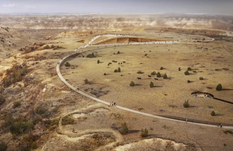 Aerial rendering of the Theodore Roosevelt Presidential Library in daylight with a pedestrian bridge and walkway surrounded by grasslands and distant buttes