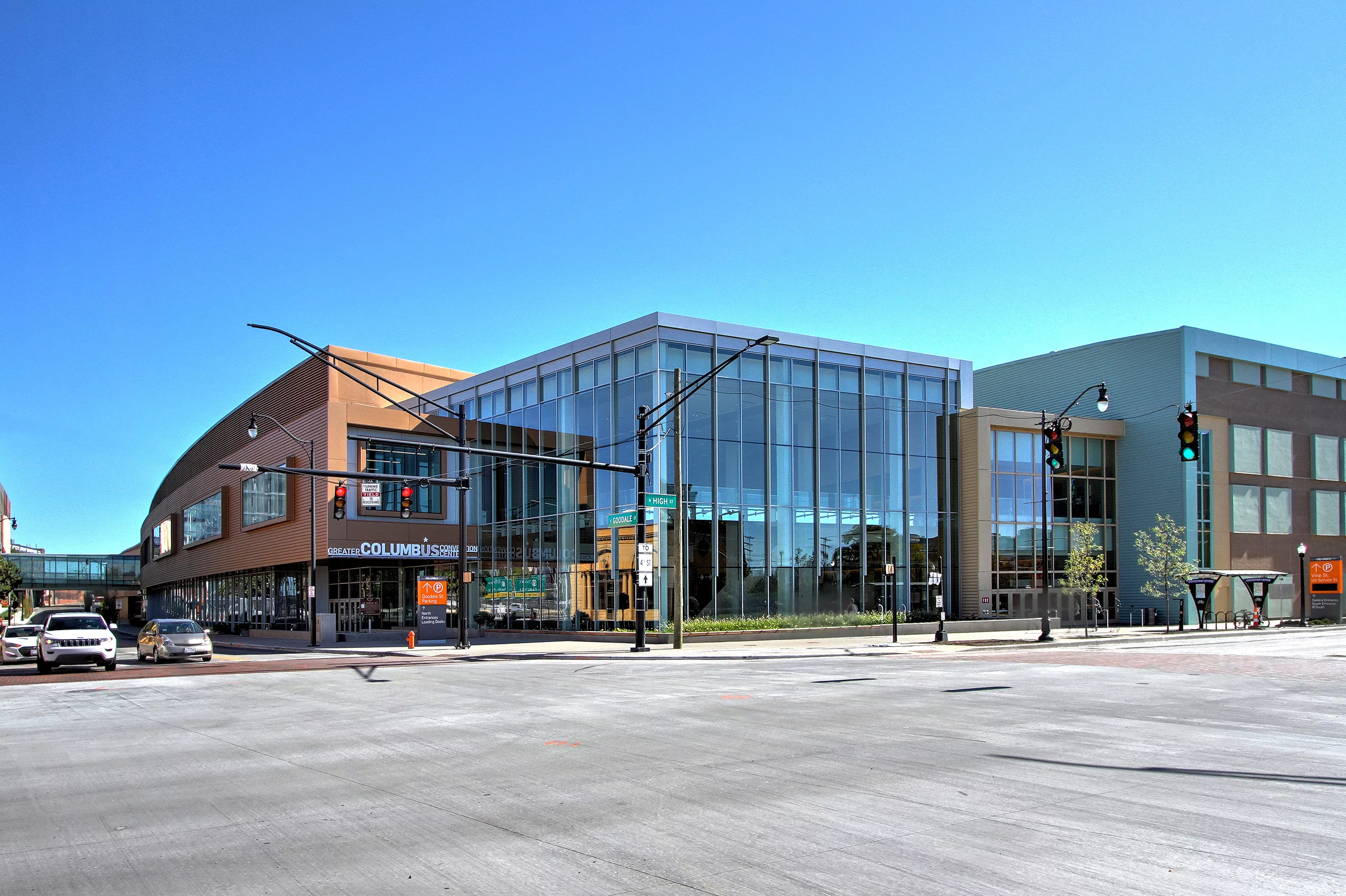 Exterior daylight view of the northwest corner of the Columbus Convention Center Renovation and Expansion with a two-story, glass-enclosed lobby and a skybridge in the distance