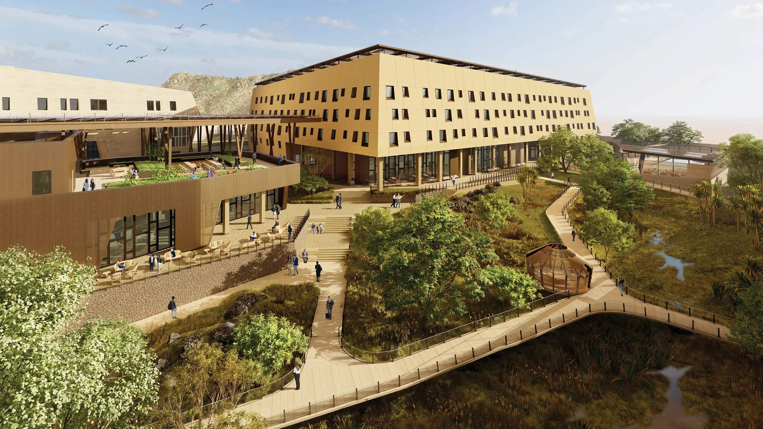 Aerial daylight rendering of the four-story, sandstone-colored U.S. Embassy in Juba surrounded by populated pathways and footbridges, natural landscaping, outdoor seating, and stairs leading to the main entrance