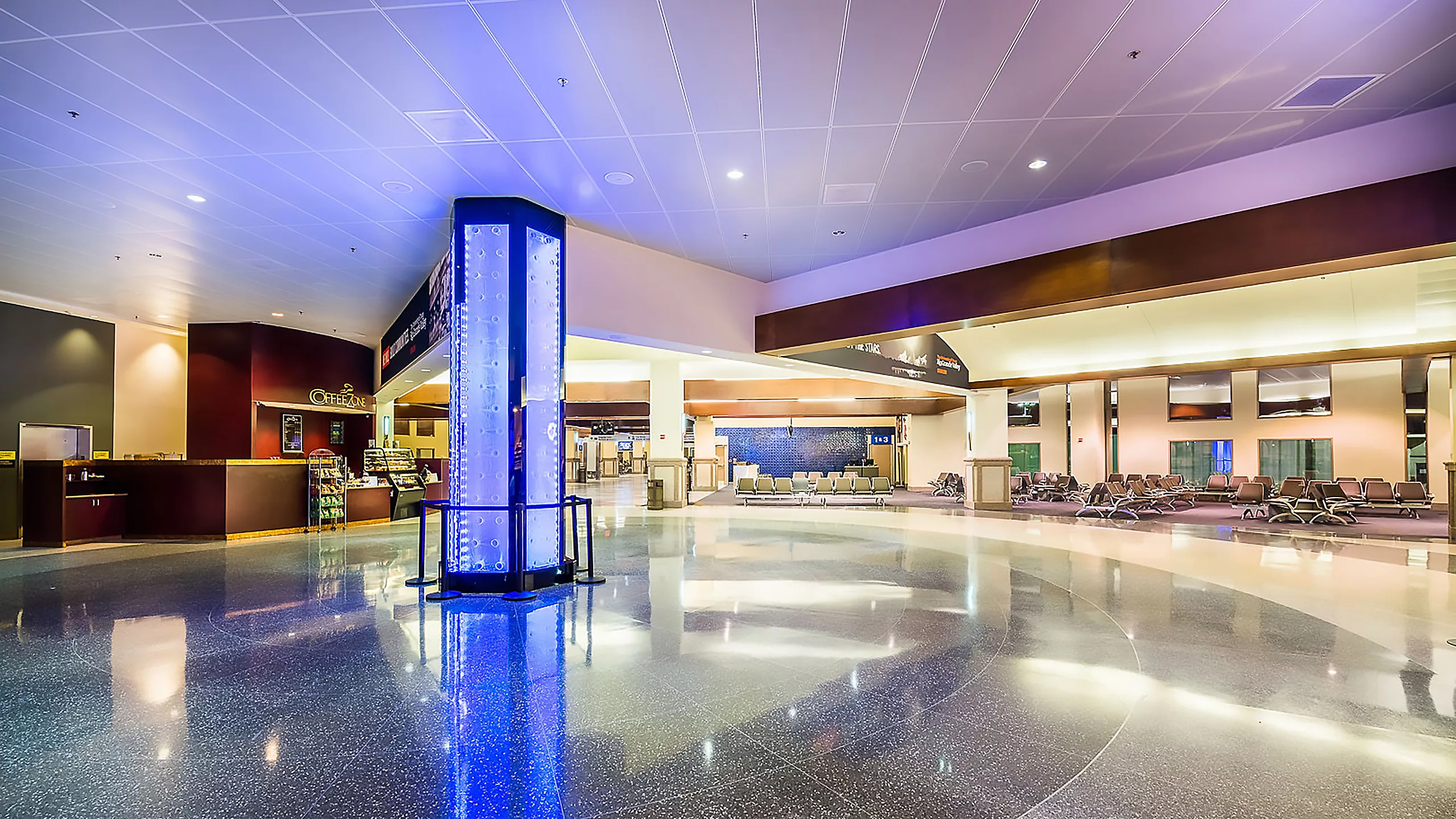 Interior image of gate seating, a coffee shop, and an illuminated pillar at the expanded McAllen-Miller International Airport