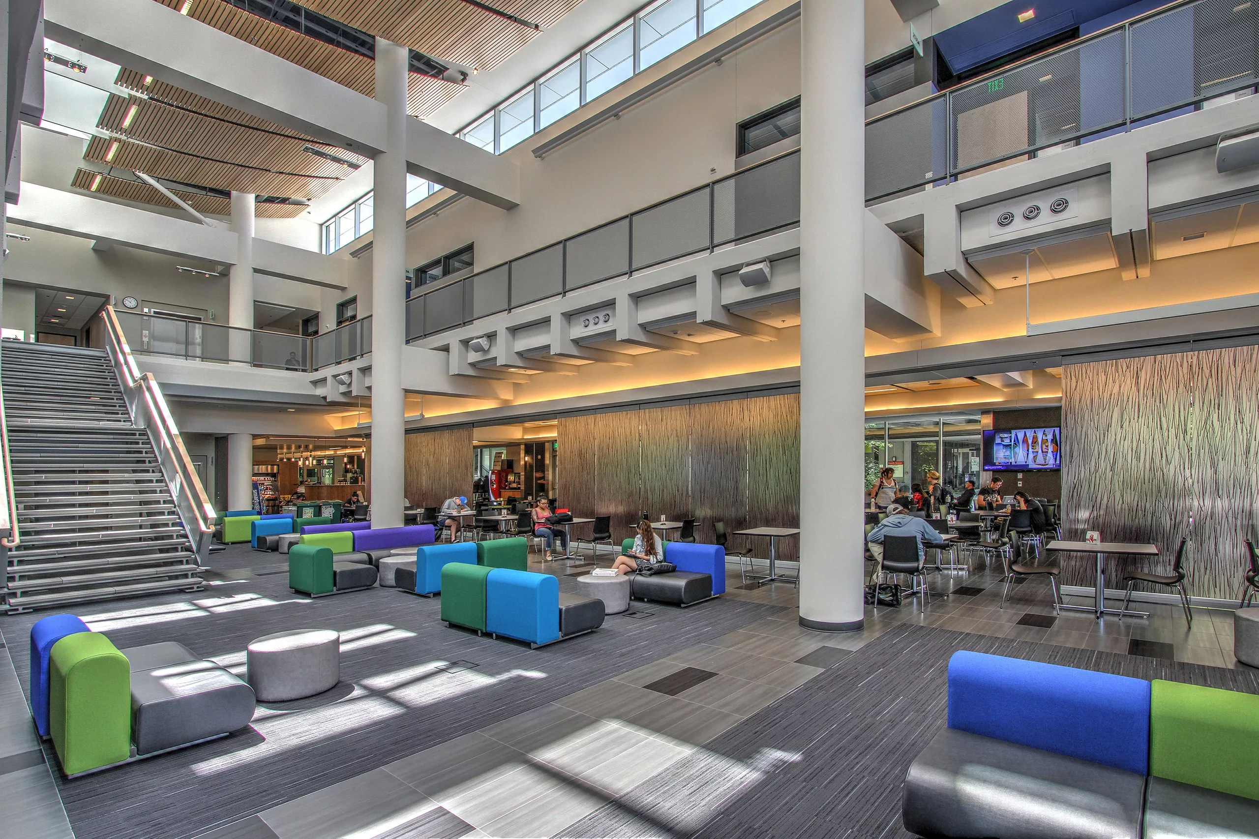 Interior daylight view of the atrium in North Seattle College's Health Sciences and Student Resources Building with views of the central staircase, cafeteria, and upstairs classrooms