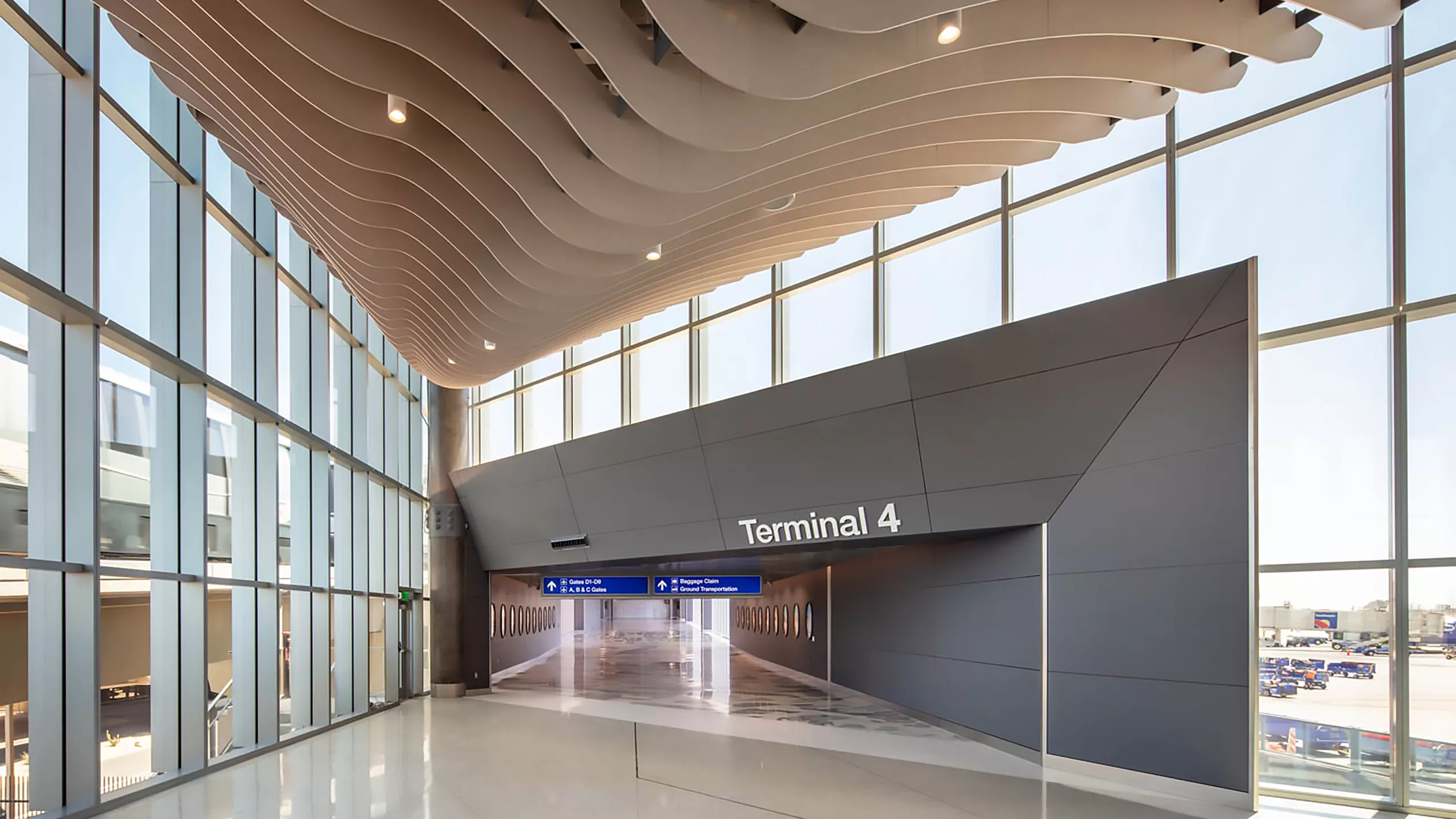 Interior daylight view of Phoenix Sky Harbor International Airport's Terminal 4 expansion featuring floor-to-ceiling windows and ornamental ceiling