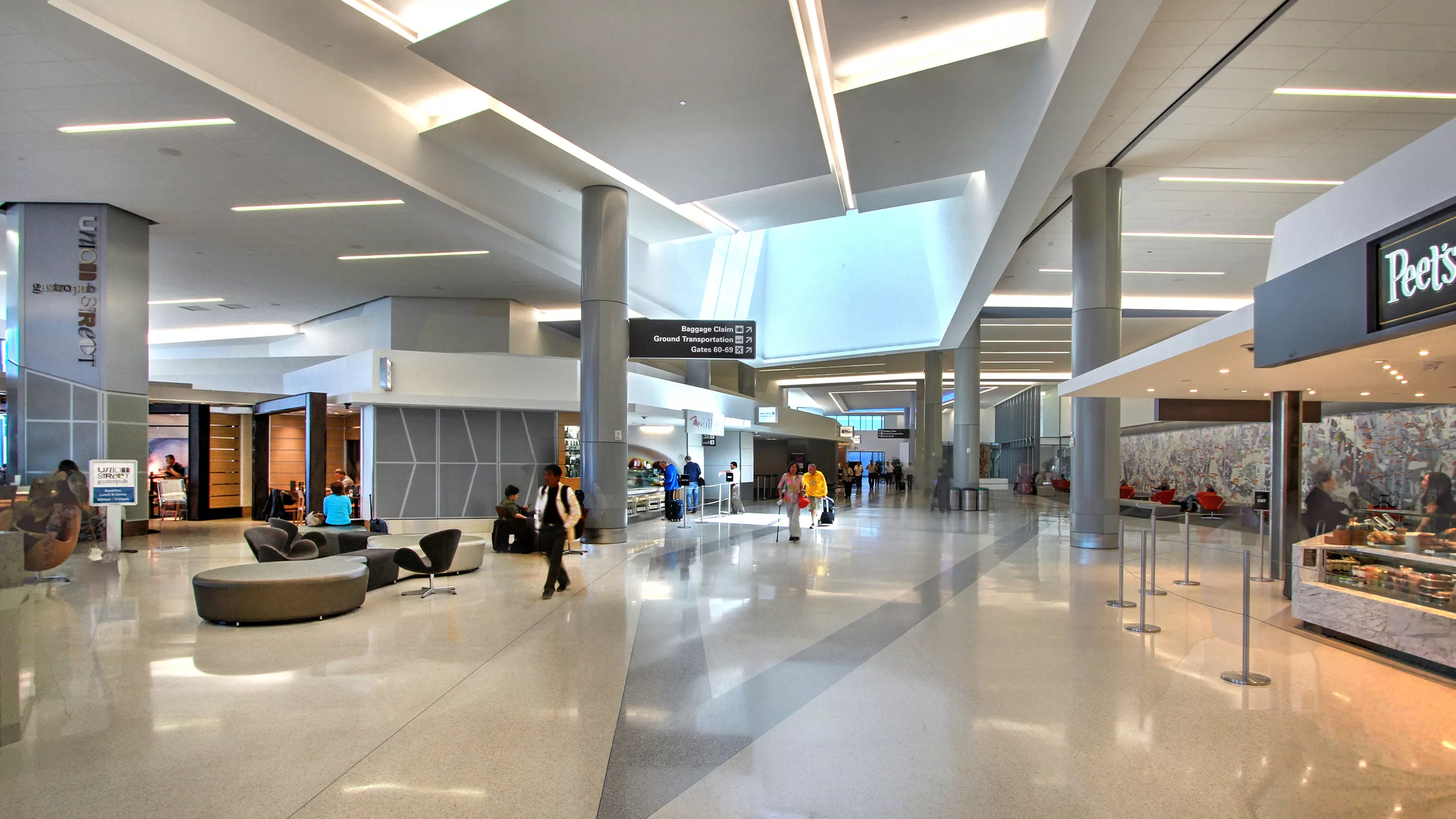Interior view of San Francisco International Airport's Terminal 3 East Retrofit and Expansion with a coffee shop and travelers moving through the concourse