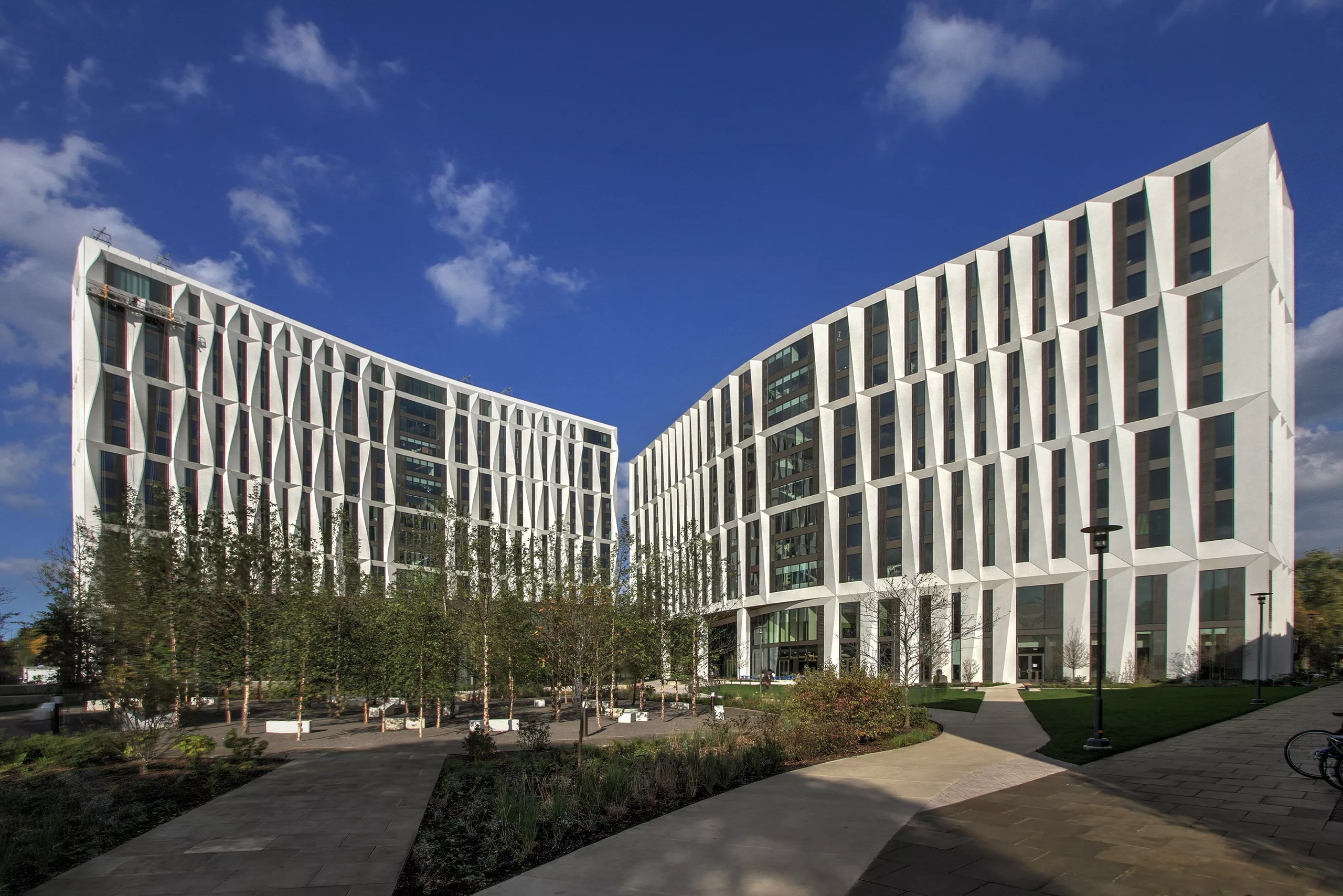 Exterior daylight view of the University of Chicago's North Residence Hall with two mid-rise buildings and an outdoor plaza containing benches, pedestrian pathways, and minimal landscaping with trees