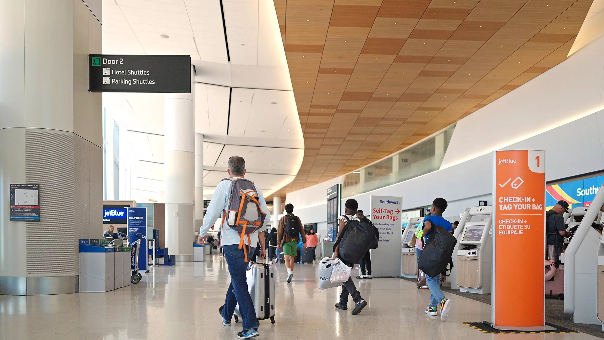 Exterior daylight view looking east toward San Diego International Airport's multi-story, glass-and-steel Federal Inspection Station fronted by steel safety bollards and minimal landscaping