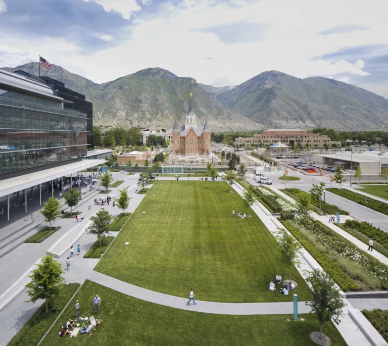 Exterior daylight view of the NuSkin Headquarters' central grounds populated by visitors and looking east toward the Provo City Center Temple