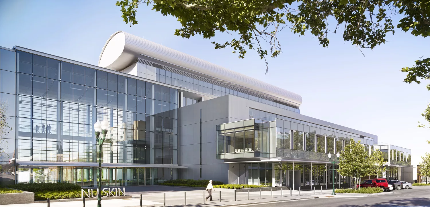 Exterior daylight view of NuSkin's Innovation Experience Center's entry plaza and glass-walled four-story atrium